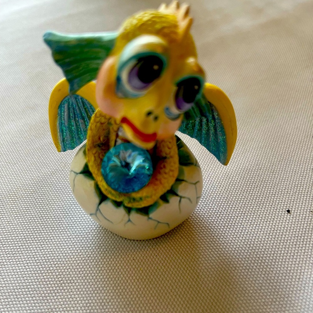 Adorable little dragon holding a blue gem. Approximately 3 inches.
